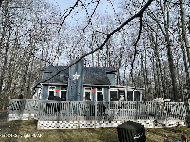 view of front of house with a front lawn, a wooden deck, and a sunroom