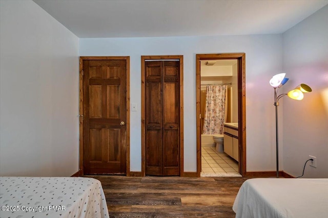 bedroom with baseboards, multiple closets, wood finished floors, and connected bathroom