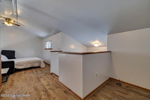 bedroom featuring lofted ceiling, baseboards, and wood finished floors