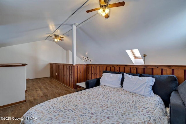 bedroom featuring lofted ceiling with skylight, ceiling fan, and wood finished floors