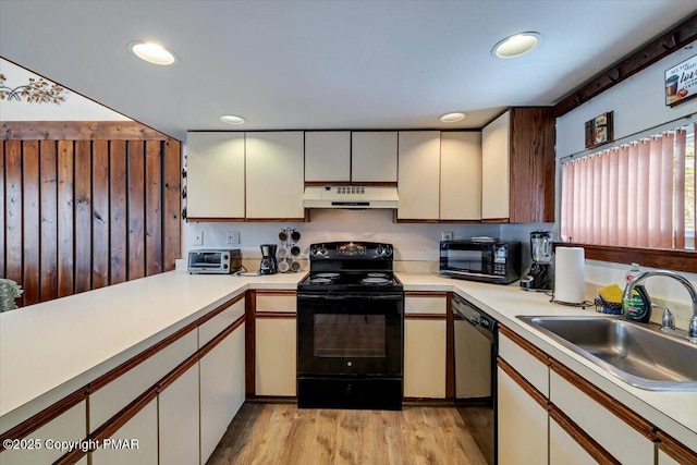 kitchen featuring under cabinet range hood, a sink, light wood-style floors, light countertops, and black appliances