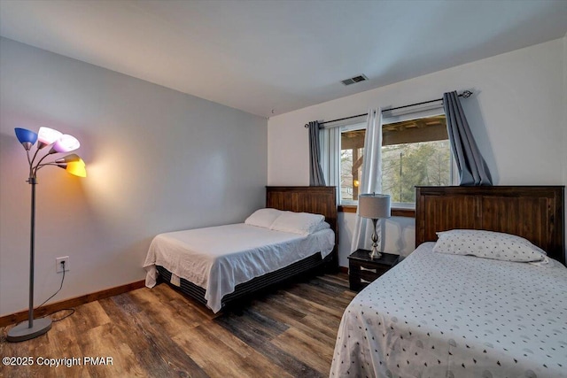 bedroom with visible vents, baseboards, and wood finished floors