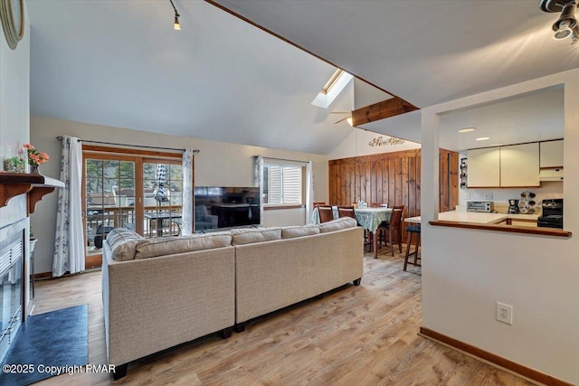 living room with a healthy amount of sunlight, lofted ceiling with skylight, and light wood-style flooring