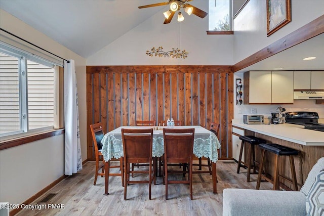 dining area with a ceiling fan, visible vents, high vaulted ceiling, and light wood finished floors