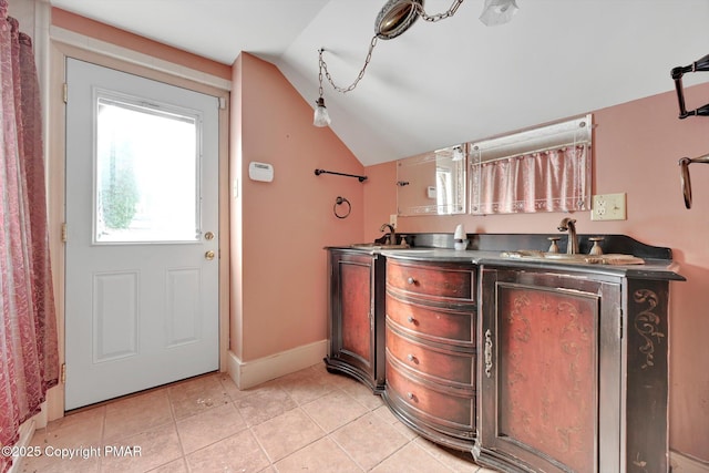 interior space featuring vaulted ceiling, light tile patterned flooring, a sink, and baseboards