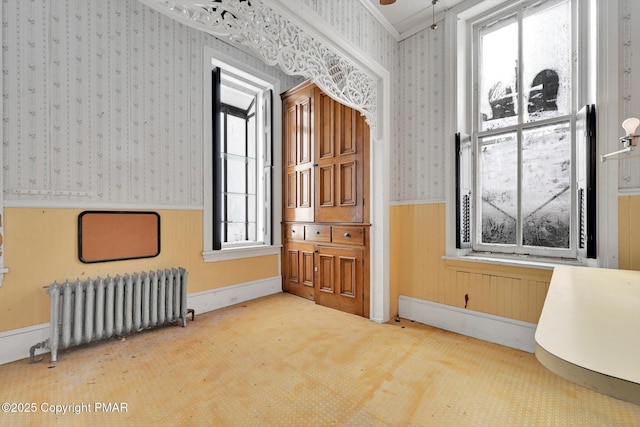 carpeted spare room featuring radiator, a wainscoted wall, and wallpapered walls