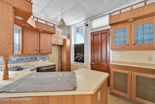 kitchen featuring dishwasher, glass insert cabinets, brown cabinets, light countertops, and a sink