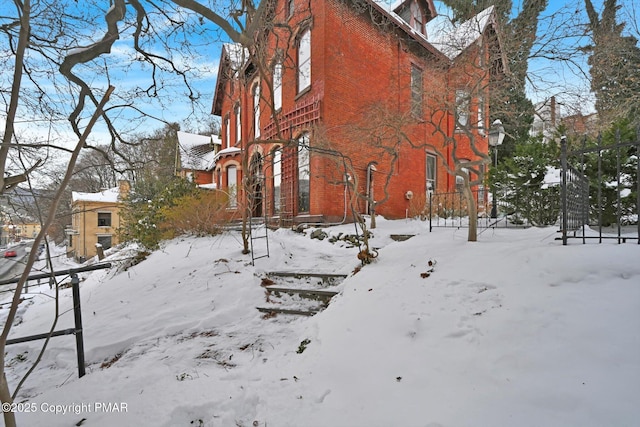 view of snowy exterior with a garage and brick siding