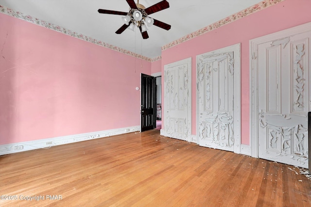 unfurnished bedroom featuring a ceiling fan, wood finished floors, two closets, and baseboards