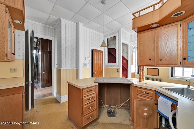 kitchen featuring wallpapered walls, a wainscoted wall, light countertops, crown molding, and a paneled ceiling