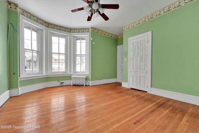 unfurnished room featuring light wood-type flooring, baseboards, and radiator heating unit