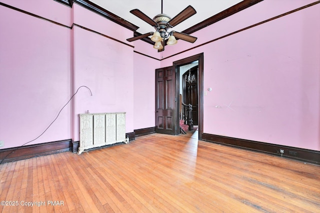 spare room with radiator, light wood finished floors, baseboards, and ornamental molding