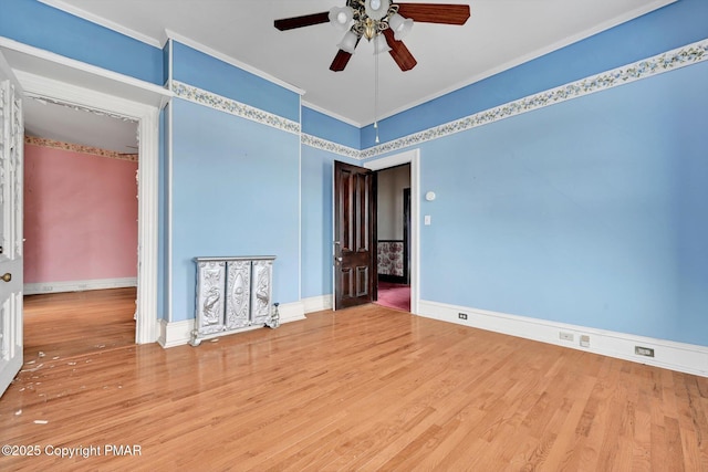 spare room with crown molding, baseboards, and wood finished floors