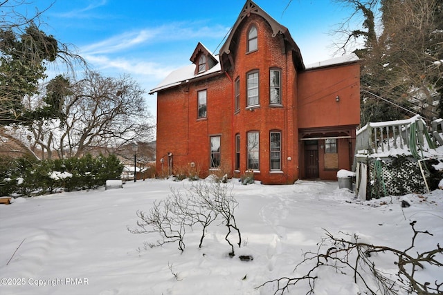 snow covered property featuring brick siding