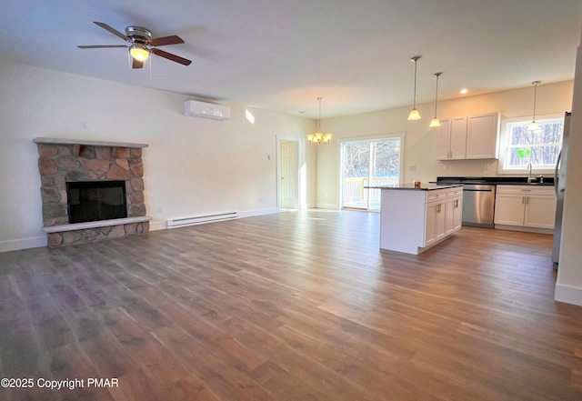 kitchen with a baseboard radiator, open floor plan, stainless steel dishwasher, a sink, and a wall mounted AC