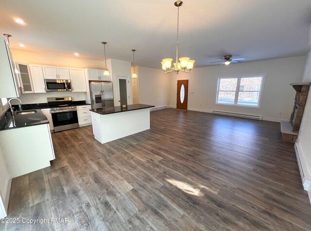 kitchen featuring dark countertops, appliances with stainless steel finishes, white cabinetry, a baseboard heating unit, and a sink