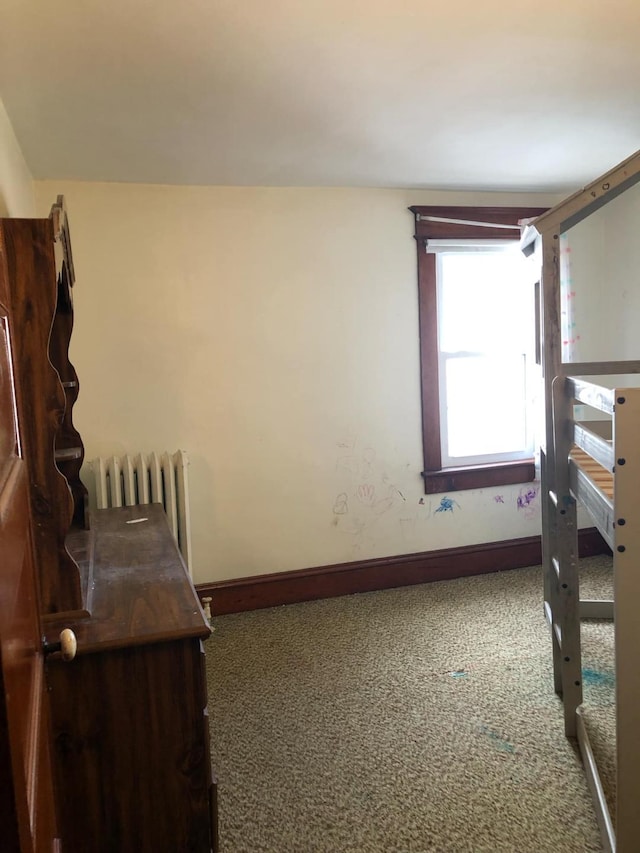 bedroom featuring carpet flooring, radiator, and baseboards