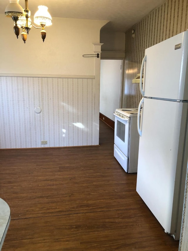 kitchen featuring dark wood-type flooring, white appliances, an inviting chandelier, wainscoting, and wallpapered walls