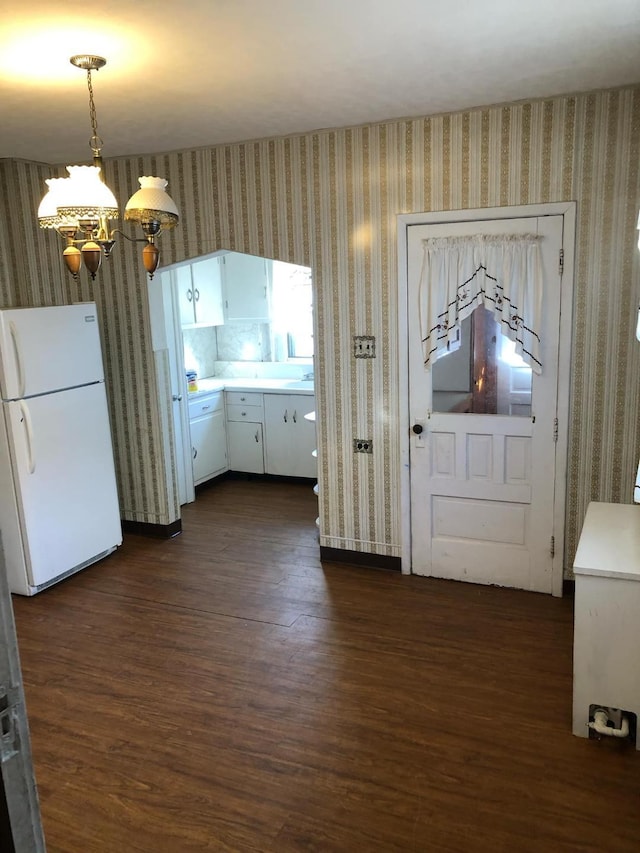 kitchen with wallpapered walls, dark wood-type flooring, a notable chandelier, and freestanding refrigerator