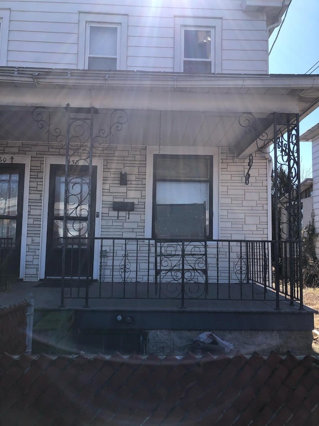 doorway to property featuring a porch and stone siding