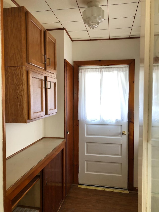 doorway to outside with a drop ceiling and dark wood-type flooring