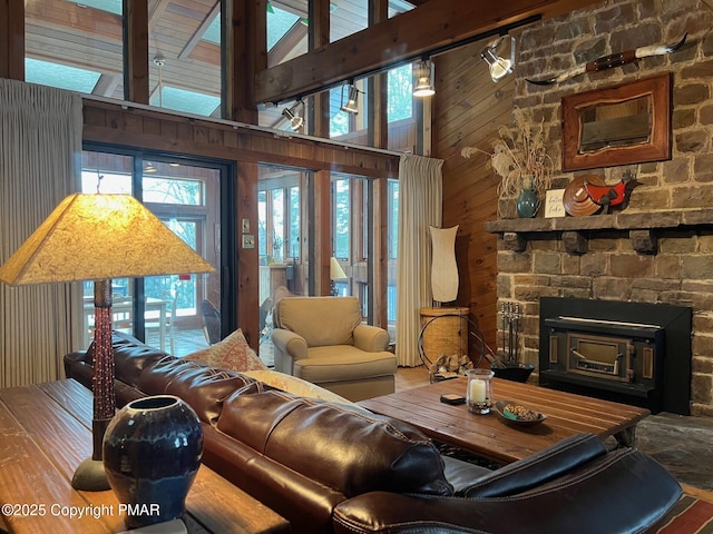 living room featuring a fireplace, high vaulted ceiling, and wooden walls