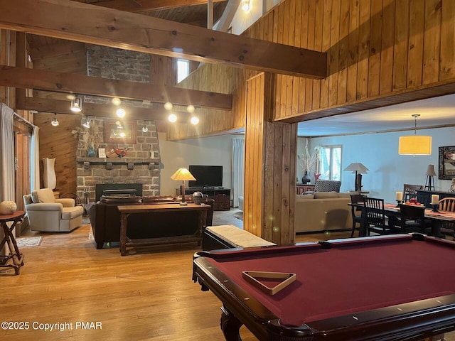 playroom with high vaulted ceiling, light hardwood / wood-style floors, wood walls, a fireplace, and beamed ceiling