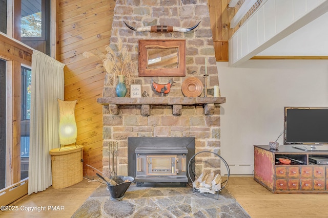 living room featuring hardwood / wood-style flooring, wood walls, and a wood stove