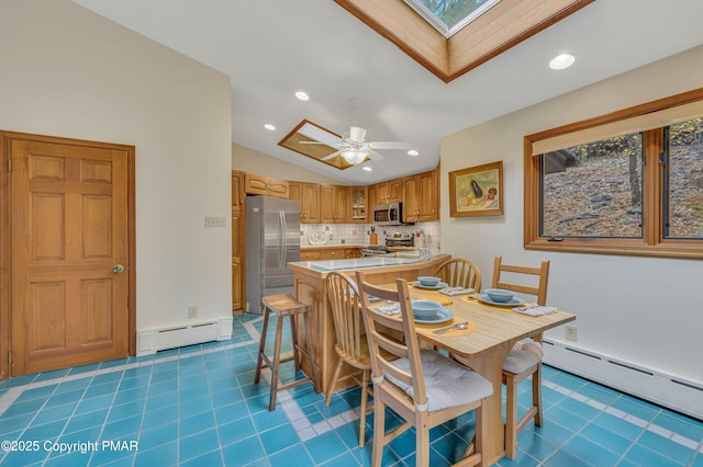 tiled dining area with a baseboard heating unit, lofted ceiling with skylight, and ceiling fan