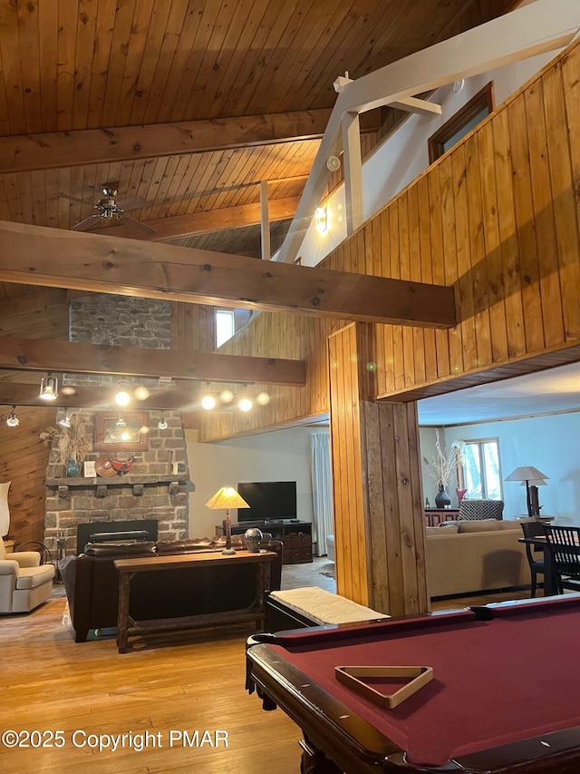 game room featuring beamed ceiling, wood walls, a fireplace, high vaulted ceiling, and billiards