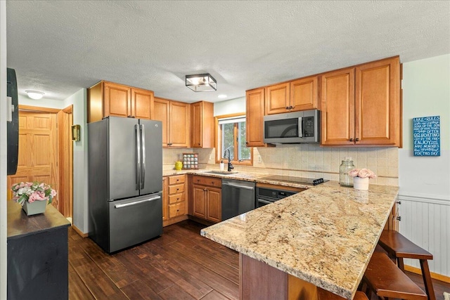 kitchen with dark wood-type flooring, a sink, a kitchen breakfast bar, stainless steel appliances, and a peninsula