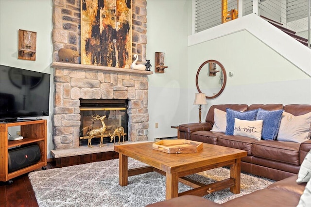 living room featuring a fireplace, wood finished floors, a towering ceiling, and a baseboard radiator