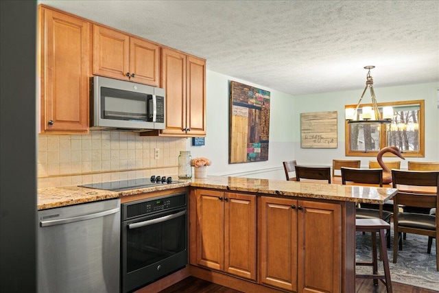 kitchen with light stone counters, a peninsula, stainless steel appliances, a kitchen breakfast bar, and backsplash