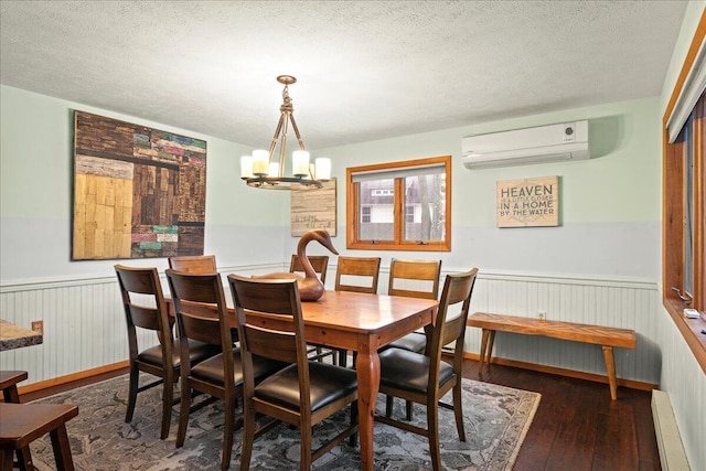 dining area with a wainscoted wall, a textured ceiling, an AC wall unit, and hardwood / wood-style floors