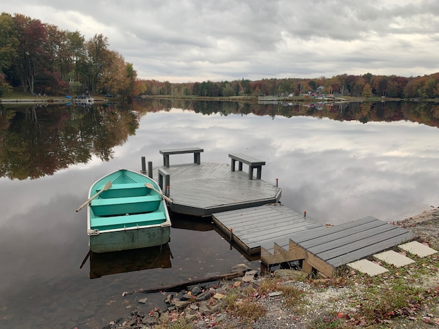 dock area featuring a wooded view and a water view