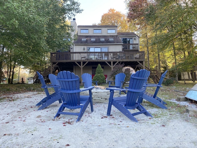 back of property featuring a shingled roof, a fire pit, a chimney, and a wooden deck