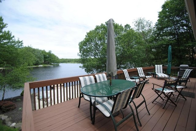 wooden terrace featuring outdoor dining space and a water view