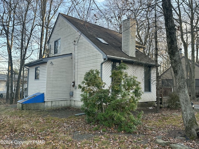 view of side of property featuring a shingled roof and a chimney