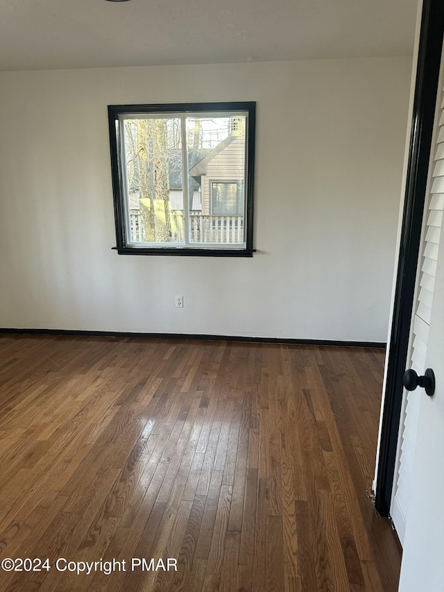 empty room featuring baseboards and dark wood-style flooring