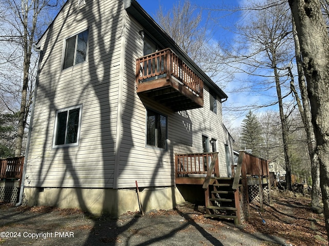 view of property exterior featuring a balcony and a wooden deck