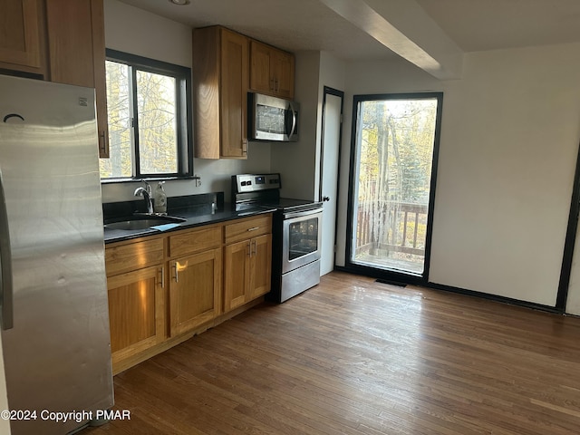 kitchen featuring a sink, stainless steel appliances, dark countertops, and brown cabinetry