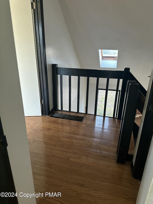 stairway featuring vaulted ceiling with skylight and wood finished floors