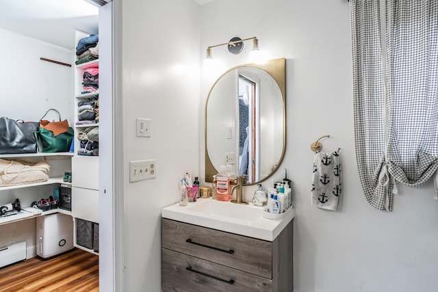 bathroom featuring wood finished floors, vanity, and baseboard heating