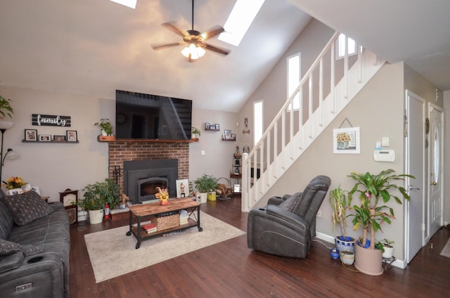 living area with ceiling fan, a fireplace, a skylight, wood finished floors, and stairway