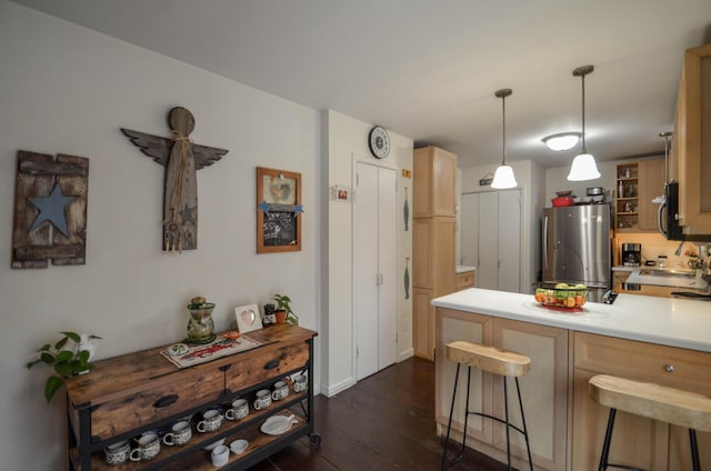 kitchen featuring dark wood-style floors, a kitchen breakfast bar, freestanding refrigerator, a peninsula, and light countertops