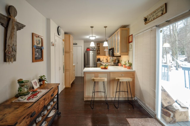 kitchen with a breakfast bar area, a peninsula, dark wood-style flooring, freestanding refrigerator, and glass insert cabinets