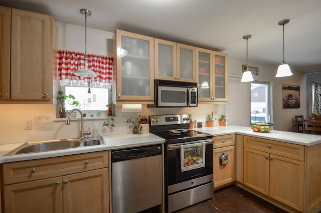 kitchen featuring a peninsula, hanging light fixtures, stainless steel appliances, light countertops, and a sink