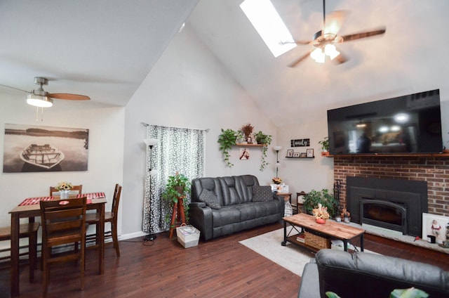 living area featuring a skylight, a ceiling fan, wood finished floors, a fireplace, and high vaulted ceiling