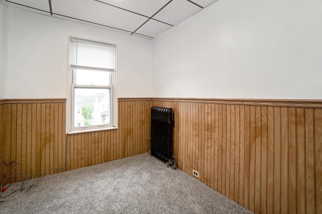 spare room with a wainscoted wall, carpet flooring, wood walls, and a paneled ceiling