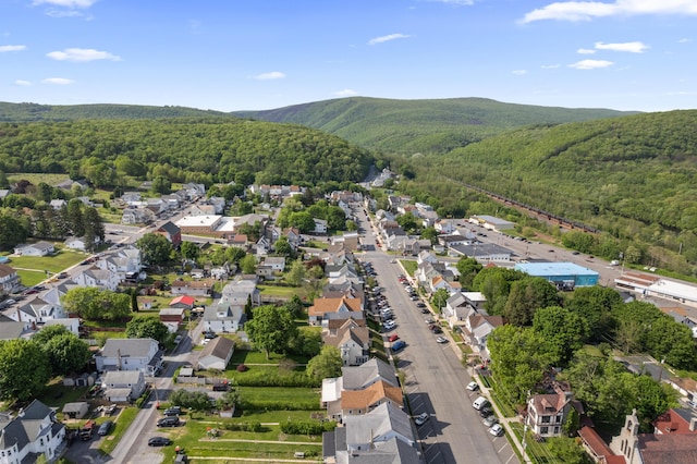 view of property location featuring a heavily wooded area, a mountain backdrop, and nearby suburban area
